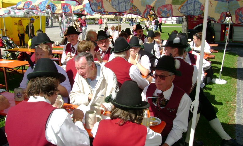 Trachtler sitzen auf den Bierbänken vor dem Rathaus.