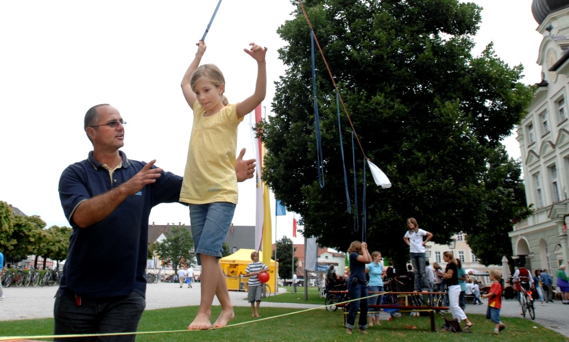 Ein Mädchen geht auf einer Slackline.