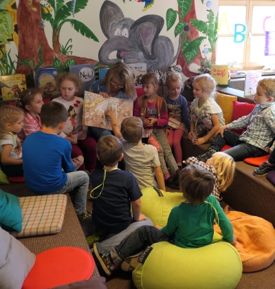 Kinder hören bei der Vorlese3viertelstunde in der Stadtbücherei Altötting aufmerksam der Vorleserin zu.