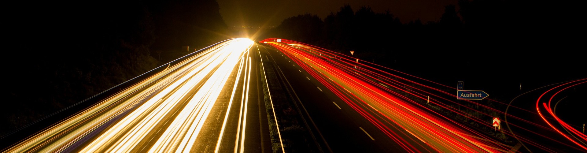 Auf einer mehrspurige Autobahn verschwimmen bei Nacht die Lichter der Autoscheinwerfer.
