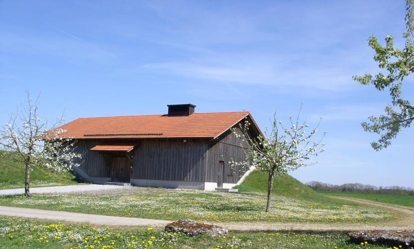 Ein Holzhaus steht auf einer Wiese, Hochbehälter Wasserwerk Altötting