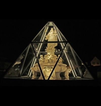 Der Marienbrunnen ist unter einer Glaspyramide bei Nacht. 
