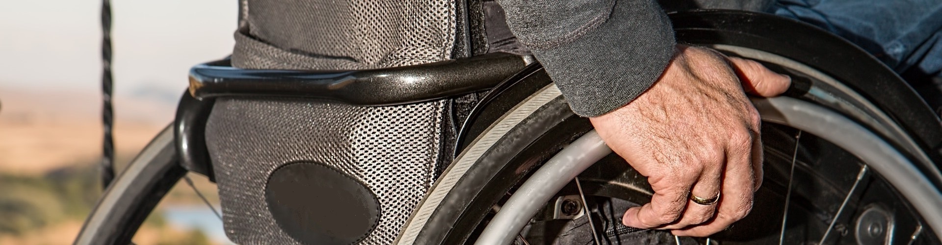 Seitenansicht eines Rollstuhls, den gerade der Rollstuhlfahrer anschiebt.