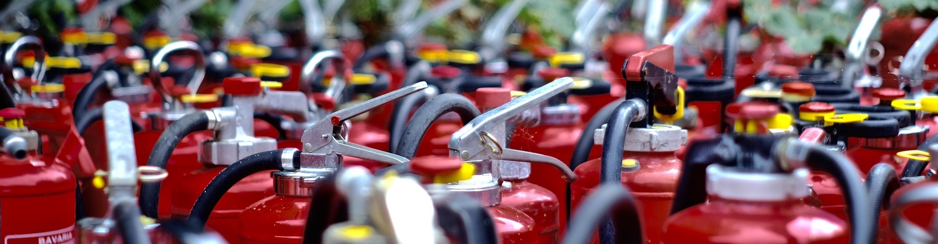 Viele rote Feuerlöscher stehen nebeneinander.