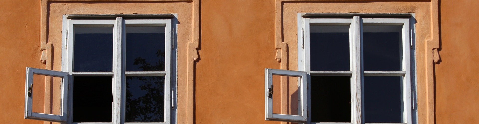 Zwei offene Fenster an einer renovierten Fassade.