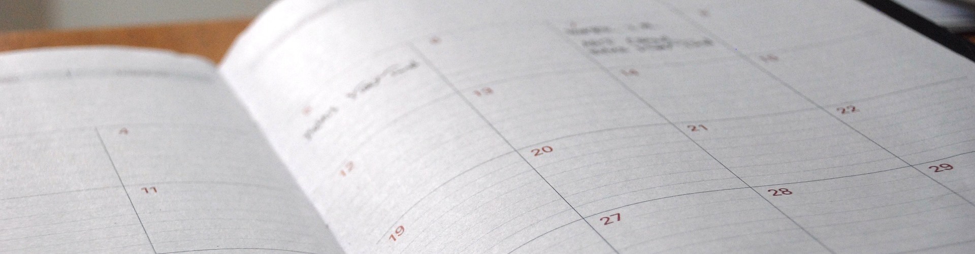 Ein aufgeschlagener Kalender liegt auf einem Holztisch.