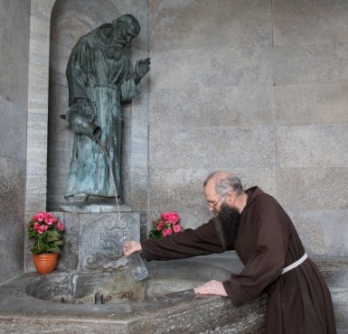 Ein Kapuziner holt sich Wasser aus dem Bruder Konrad Brunnen.