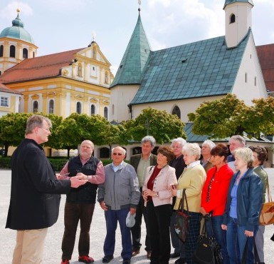 Eine Stadtführung, bei dem am Altöttinger Kapellplatz gerade etwas erzählt wird.