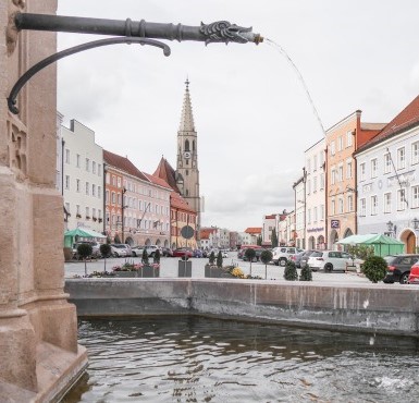 Blick vom Stadtbrunnen auf den Stadtplatz in Neuötting und auf die Pfarrkirche St. Nikolaus.