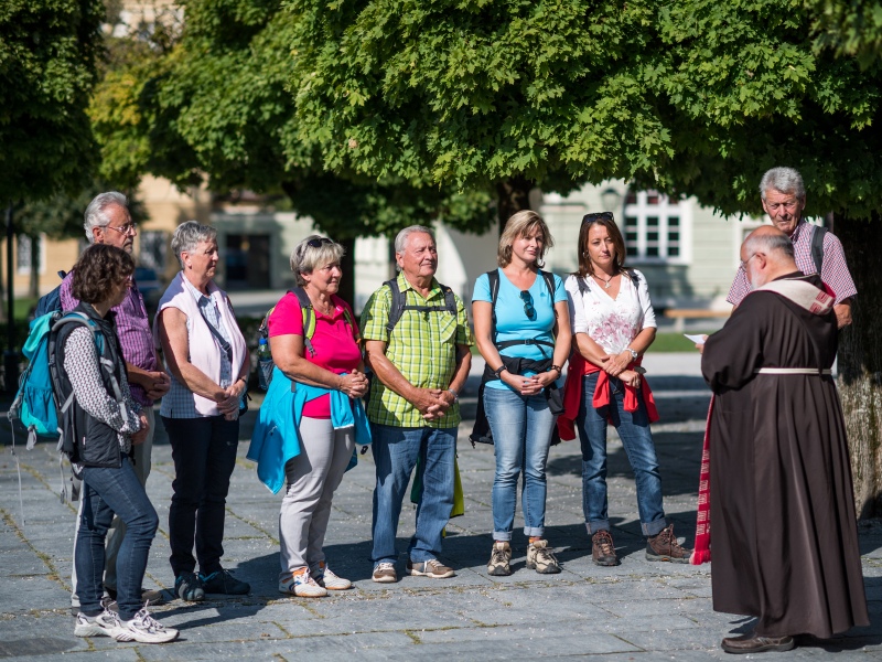 Pilger stehen am Kapellplatz und ein Kapuziner gibt den Pilgersegen.