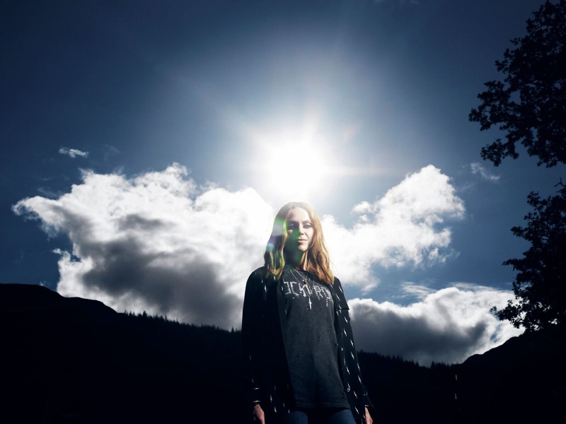 Amy Macdonald in der Natur mit Sonnenschein im Hintergrund.