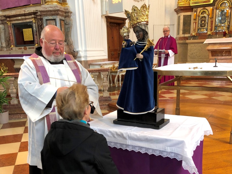 Eine Dame kniet vor der Altöttinger Madonna in einer Kirche. 