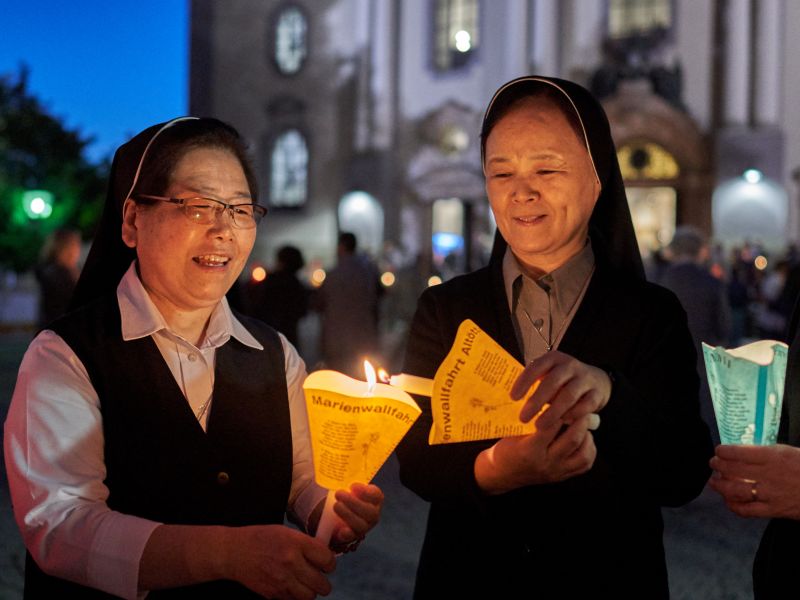 Schwestern entzünden Kerzen vor der Lichterprozession