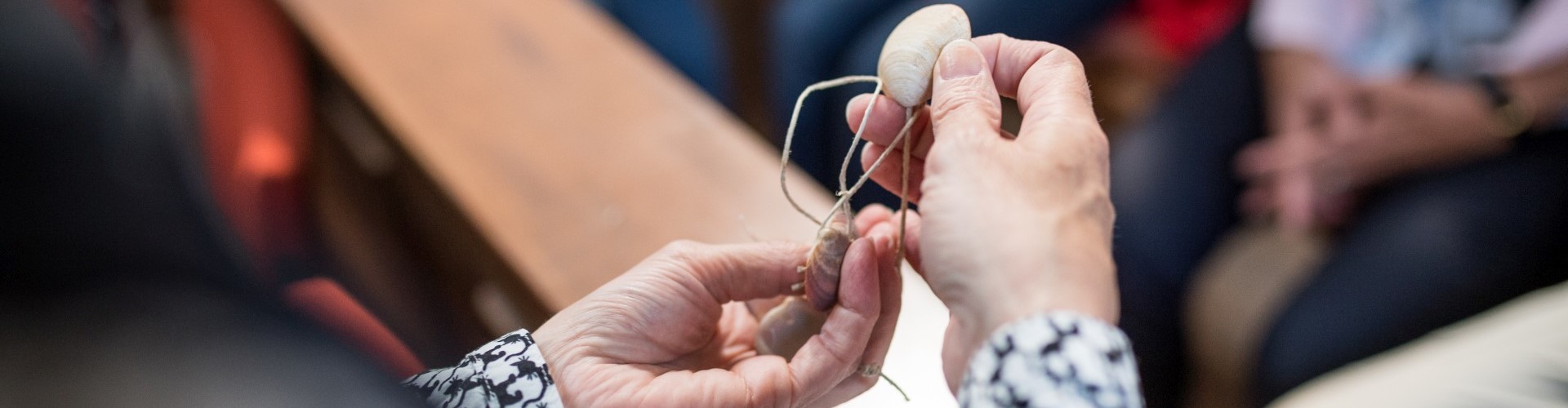 Eine Pilgerin in Altötting hat Jakobsmuscheln in der Hand, die mit einem Strick verbunden sind.