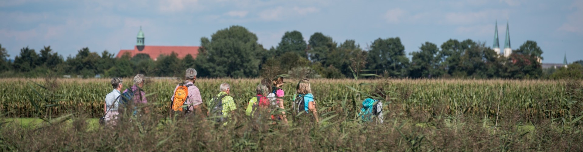 Eine kleine Pilgergruppe geht vor dem Stadtpanorama von Altötting.