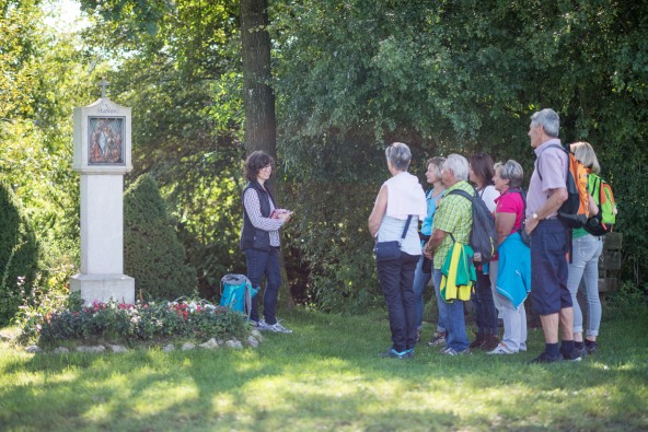 Eine kleine Pilgergruppe die an einer Station des Kreuzwegs von Heiligenstatt nach Altötting steht.