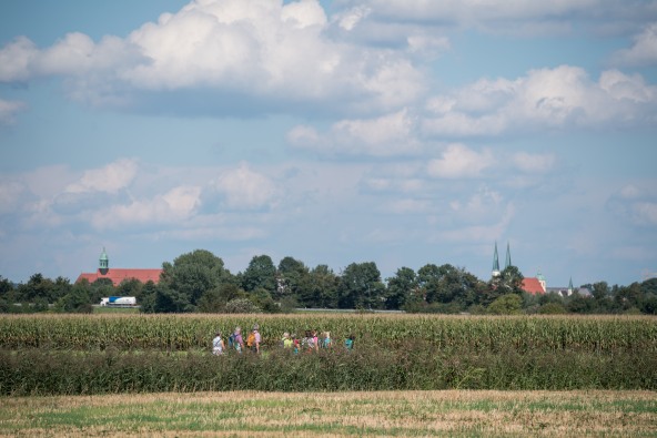 Eine kleine Pilgergruppe, die vor dem Stadtpanorama nach Altötting gehen.