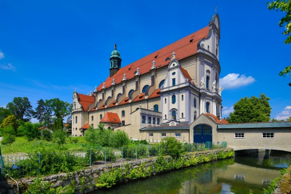 Eine Aussenansicht der Altöttinger Basilika St. Anna, mit dem Mörnbach im Vordergrund.