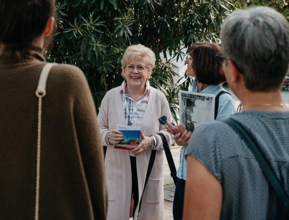 Drei Frauen hören einer Stadtführerin zu.