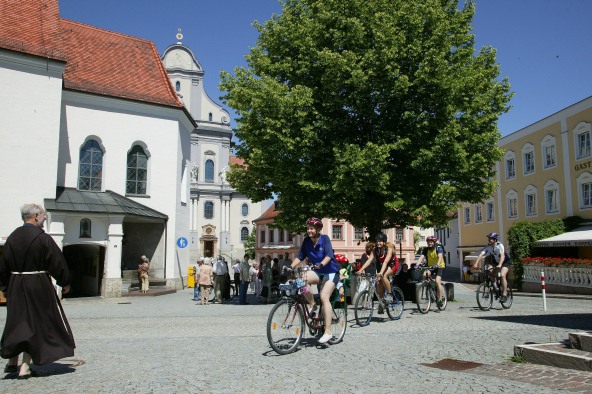 Eine kleine Radfahrergruppe auf dem Benediktweg an der Papstlinde in Altötting.