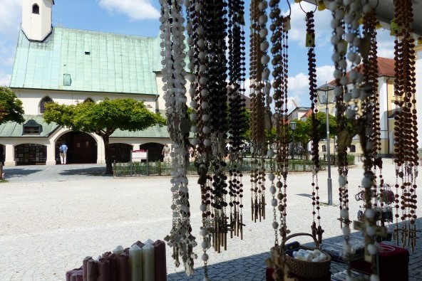 Verschiedene Rosenkränze in einem Geschäft auf dem Altöttinger Kapellplatz, mit Blick auf die Gnadenkapelle.