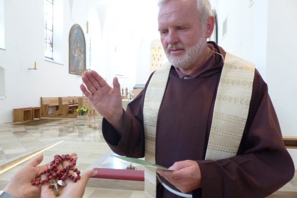 In der Altöttinger Hl. Bruder Konrad Kirche wird von einem geistlichen ein Rosenkranz gesegnet.