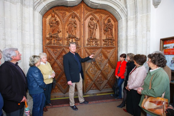 Eine Stadtführung in Altötting, bei der gerade verschiedene Schnitzereien einer Holztüre erklärt werden.