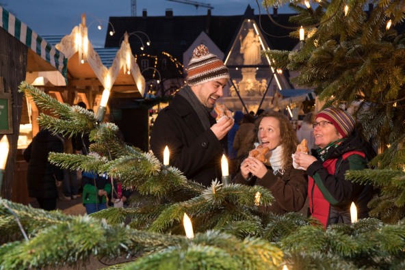 Eine kleine Gruppe genießt auf dem Altöttinger Christkindlmarkt einen leckeren Zimtstern.