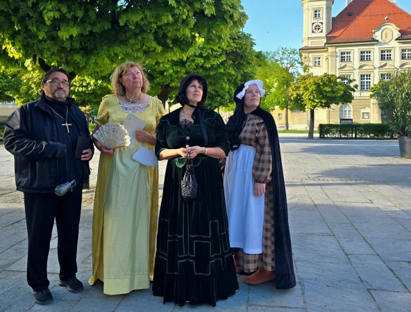 Vier altertümlich gekleidete Menschen stehen auf dem Kapellplatz.