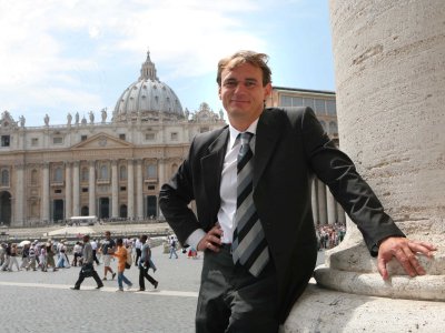 Ein Herr im schwarzen Anzug steht vor dem Petersdom in Rom. 