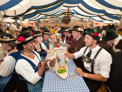 Menschen in Tracht sitzen im Bierzelt und trinken Bier. 