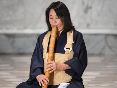 Eine Frau spielt auf einer Japanischen Bambusflöte. 