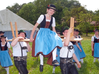 Zwei Burschen in Lederhosen tragen in Dirndl, das auf einer Bank sitzt.