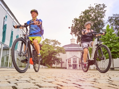 Zwei Radler fahren vom Panorama zum Kapellplatz.