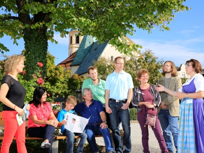 Stadtführung in Altötting, Foto Heiner Heine Eine Stadtführungsgruppe steht am Kapellplatz unter einem Baum.