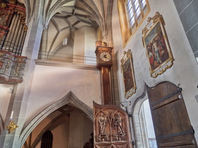 Die große hölzerne Standuhr mit einem Sensenmann oben drauf in der Stiftskirche Altötting. 