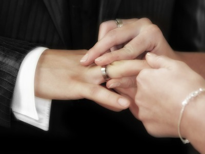 Eine Frau steckt ihrem Mann den Ring an den Finger.