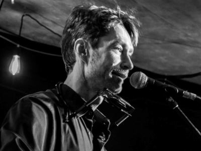 Ein schwarz-weiß Foto von einem Mann, der ins Mikrofon singt. 