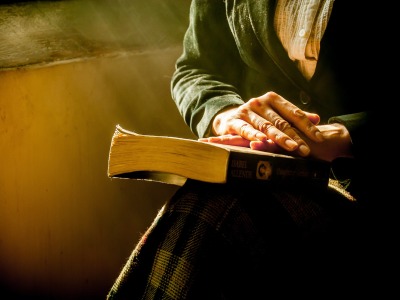 Eine Frau betet mit einer Bibel auf dem Schoß 